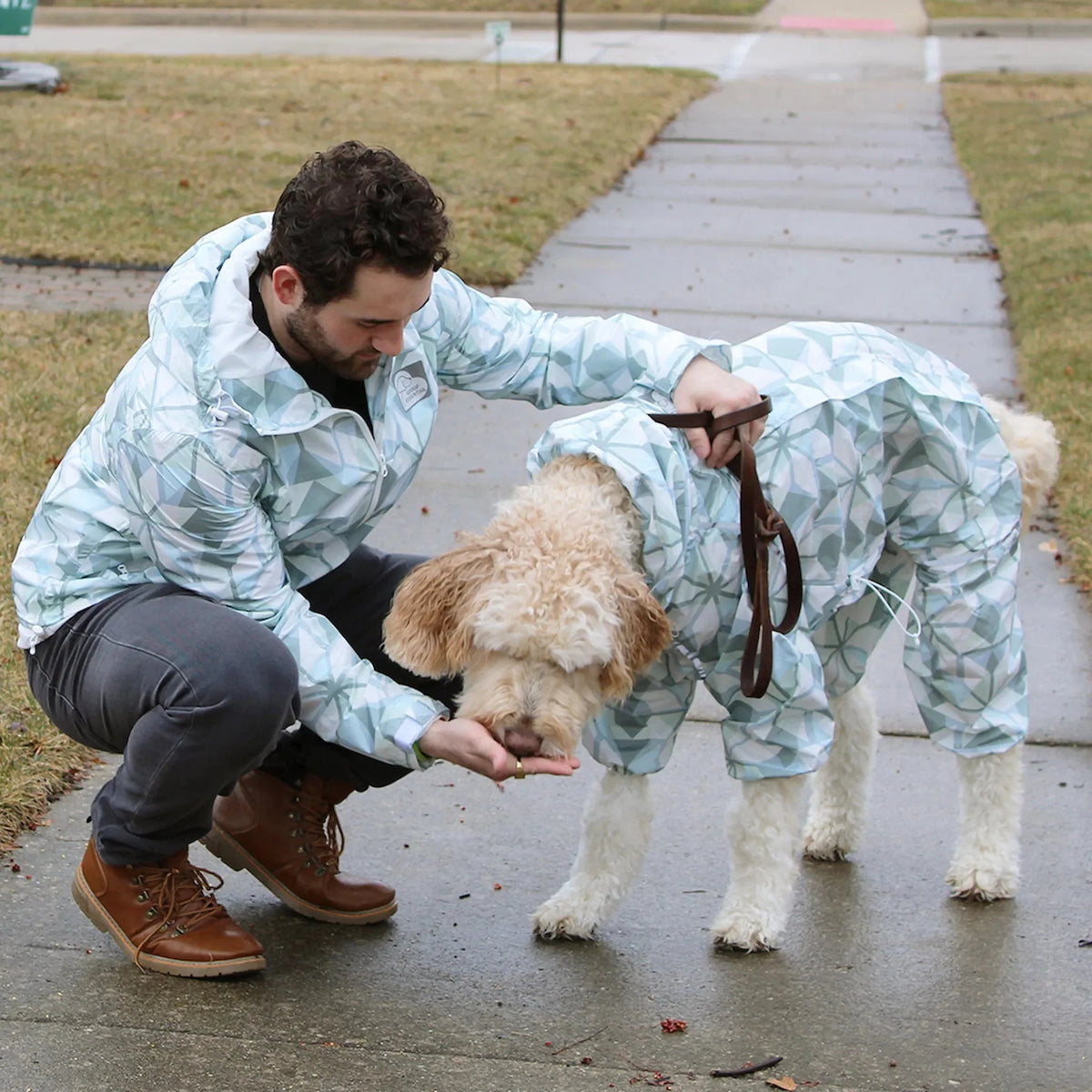 Owner and dog in matching Overcast raincoats on a wet sidewalk
