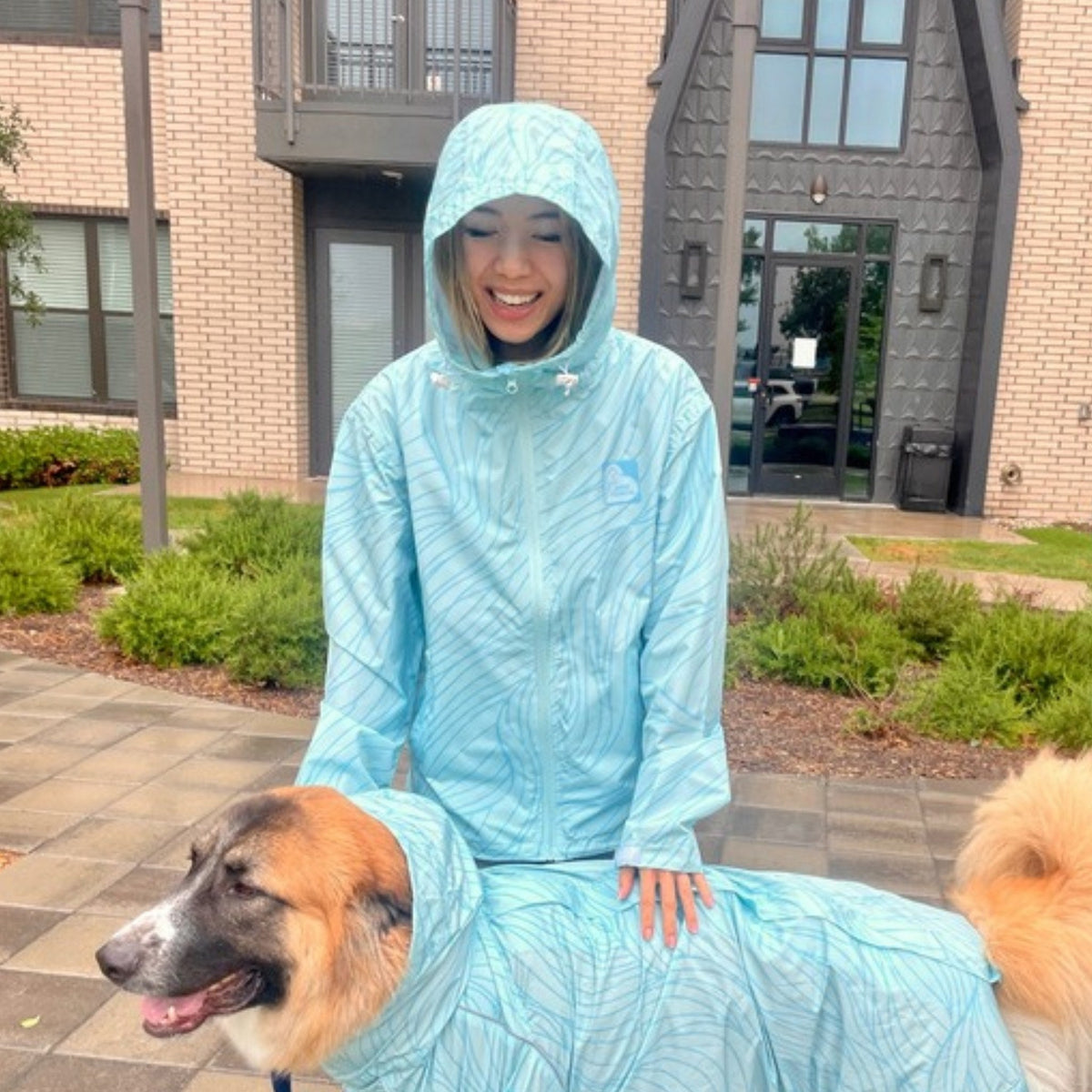 Owner in the Ripple raincoat with her dog in the matching coat outside 
