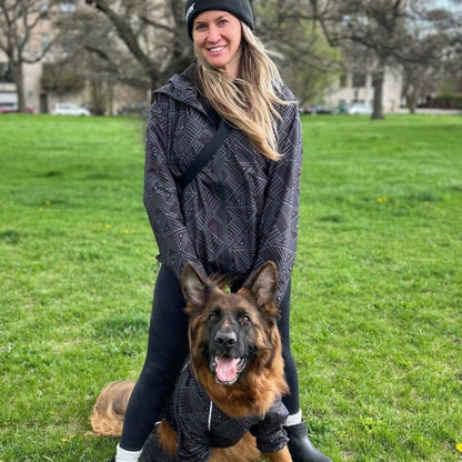 Owner and German shepherd in matching Eclipse raincoats in the park 