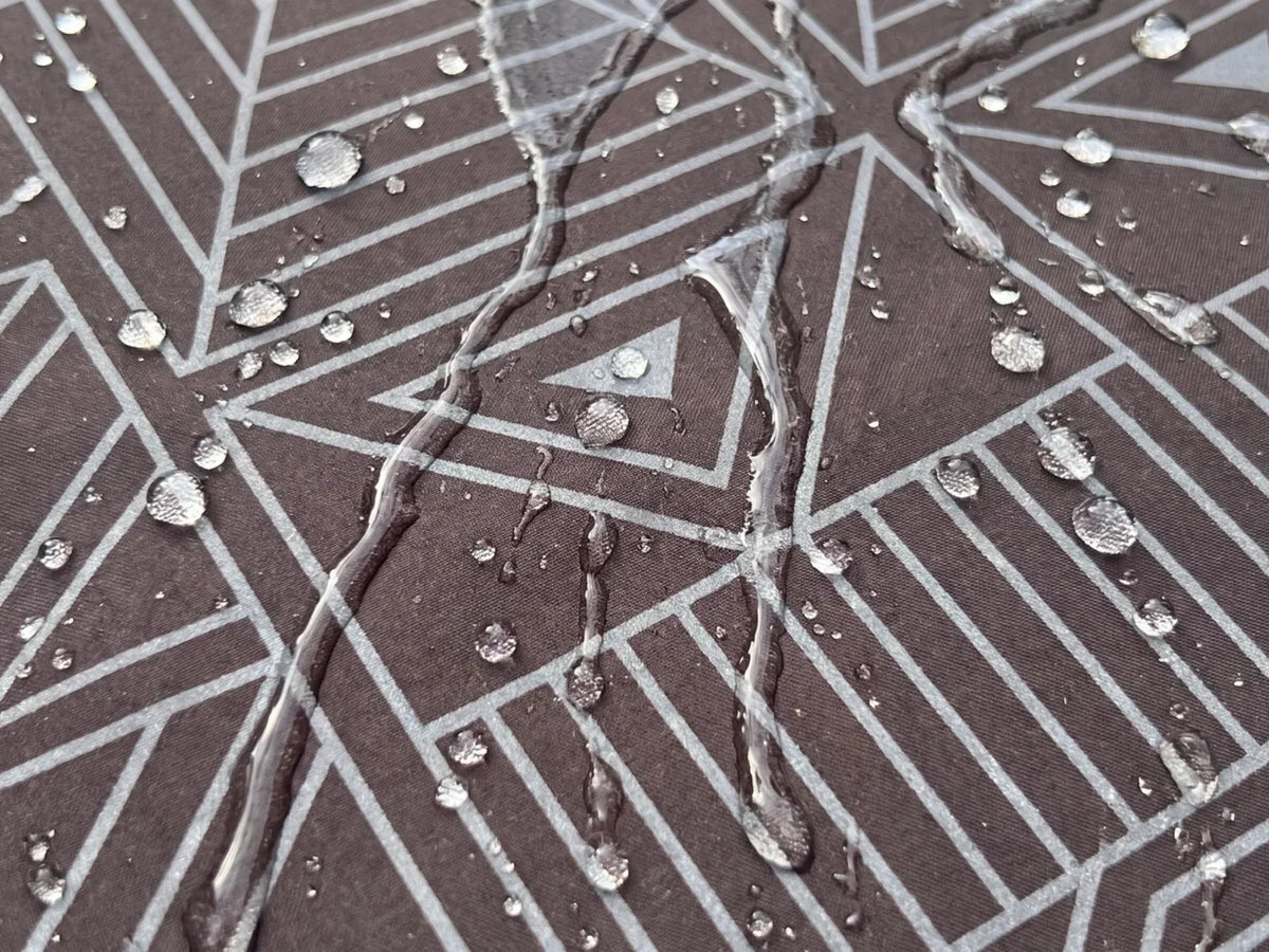 Water beading and running off the surface of a dark dog raincoat fabric