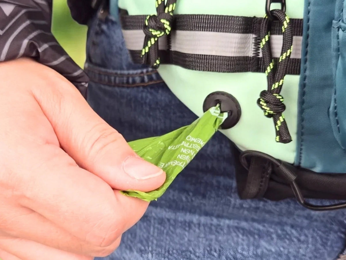 Pulling a poop bag from the built-in dispenser on the side of the hip pack