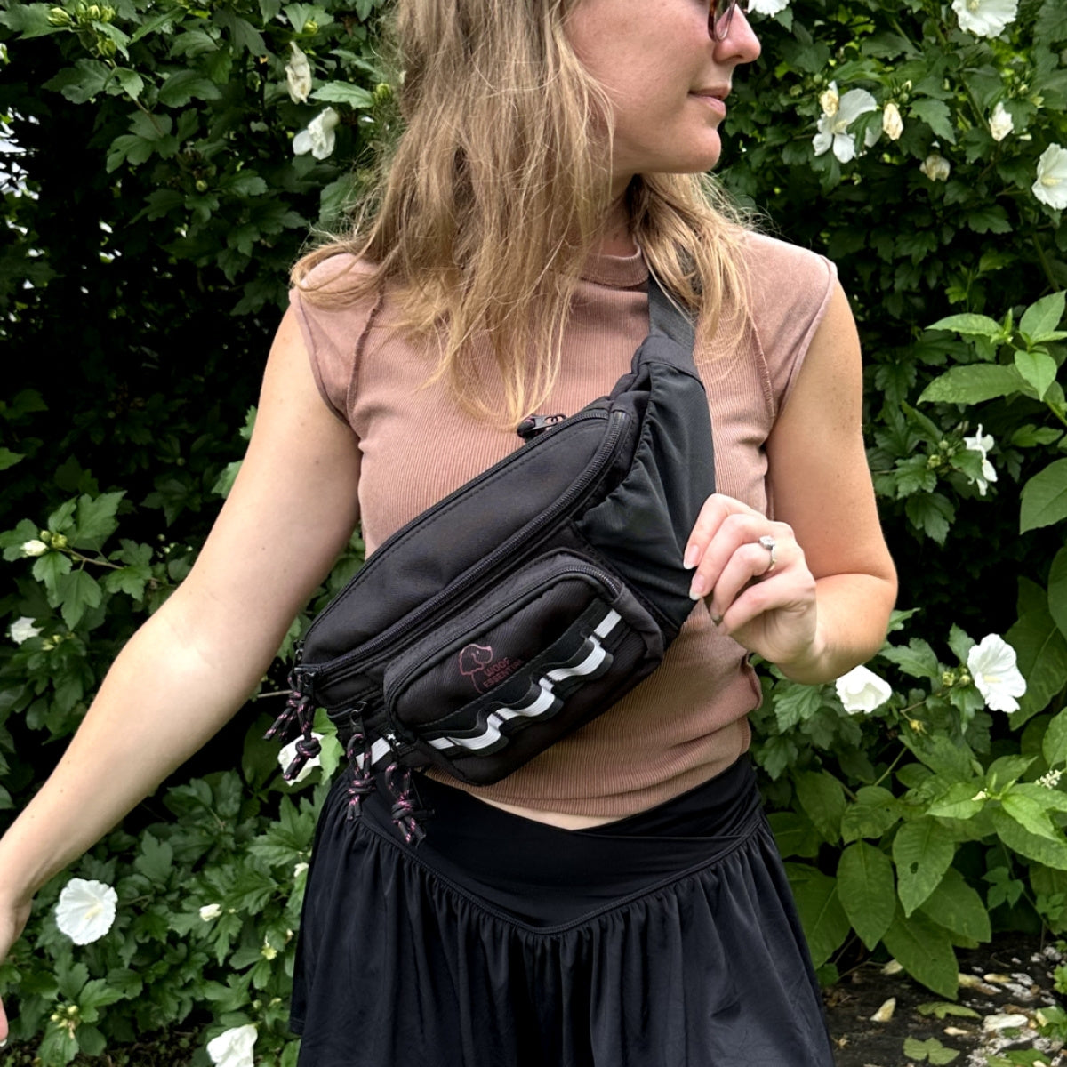 Black Hip Pack 2.0 worn crossbody in a garden