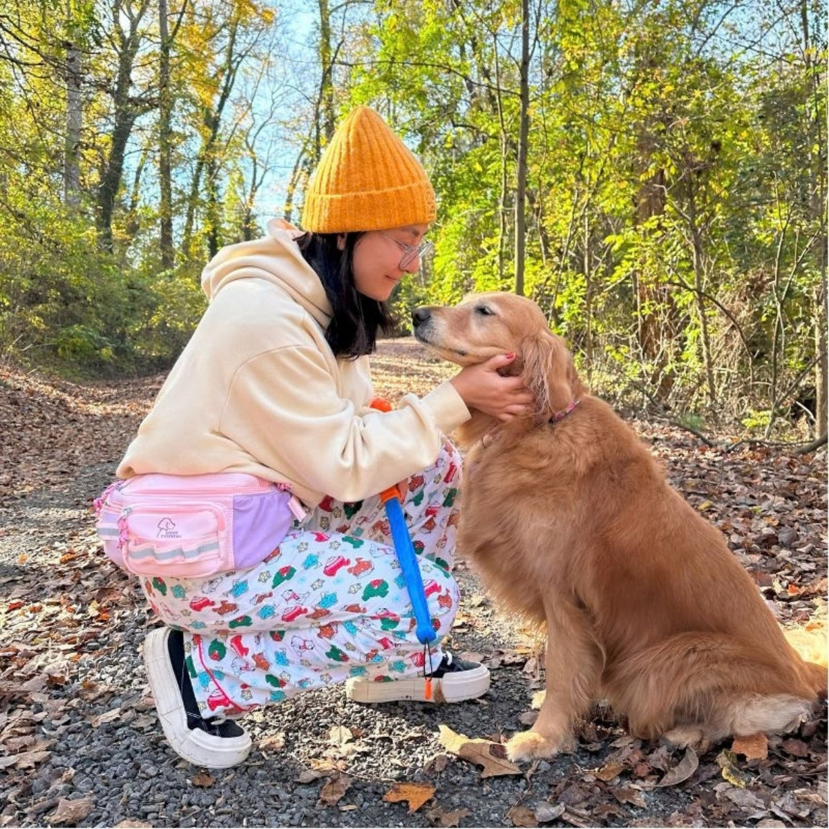 Pink Hip Pack 2.0 on a fall trail with a golden retriever