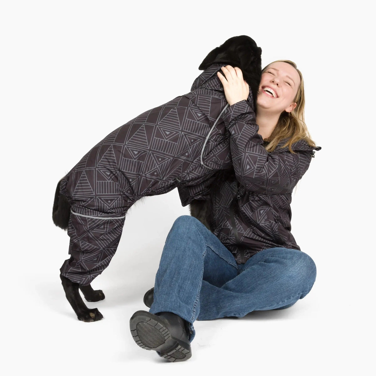 Owner hugging her black dog, both in Eclipse Puddle Jumper raincoats 