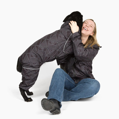 Owner hugging her black dog, both in Eclipse Puddle Jumper raincoats 