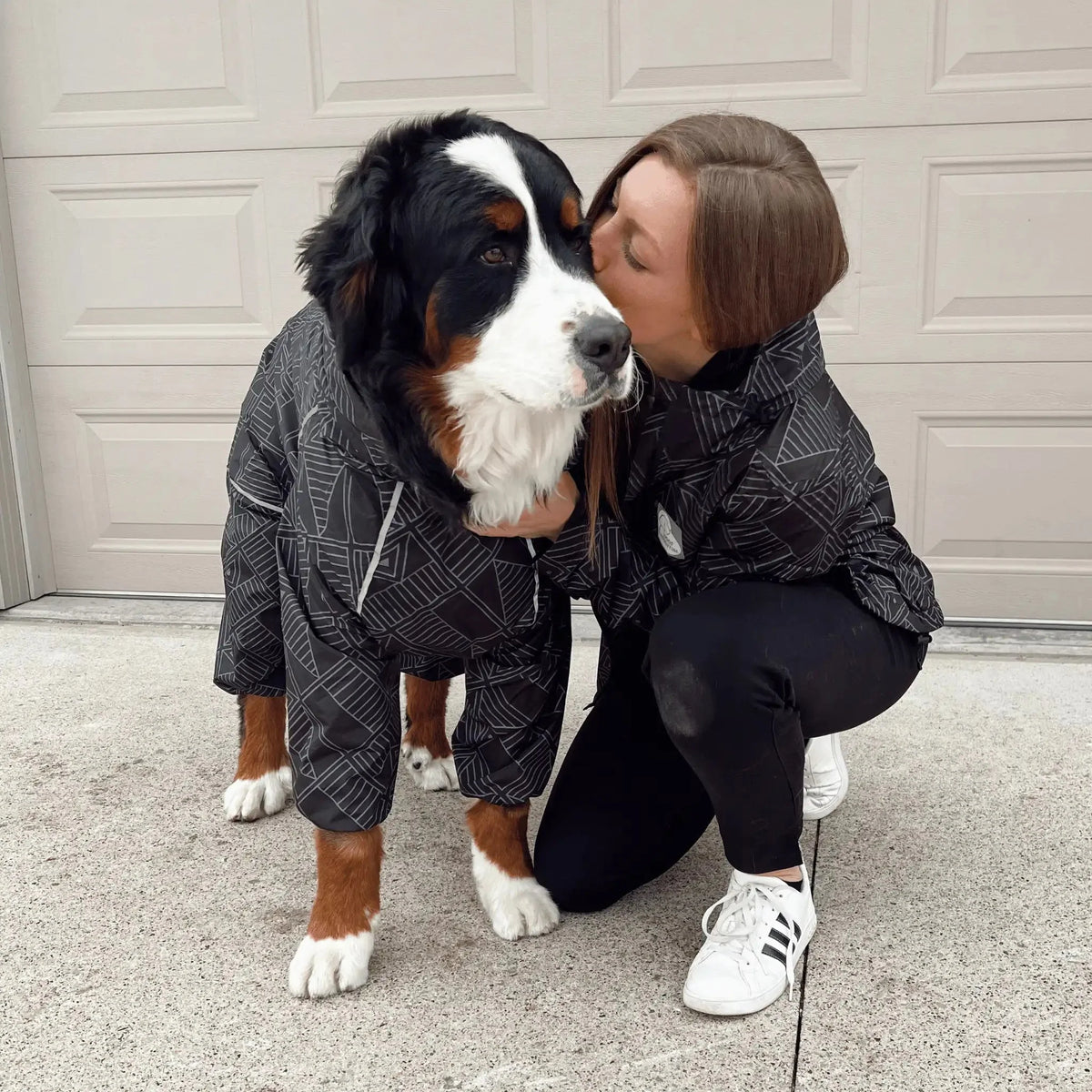 Owner and Bernese mountain dog in matching Eclipse raincoats on a driveway 