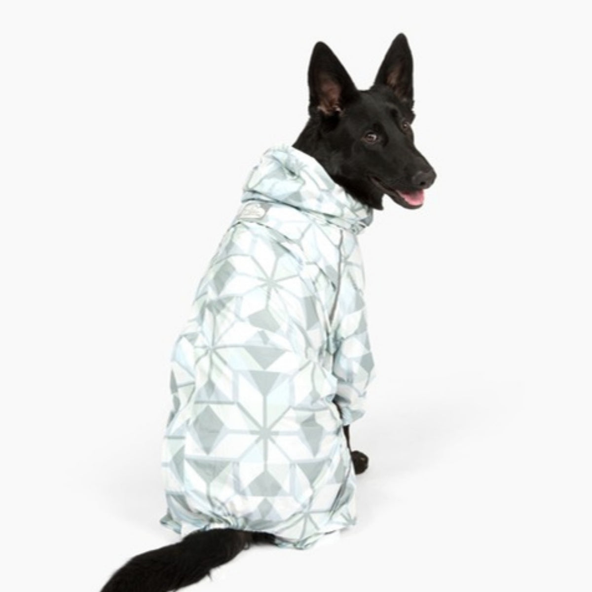 Black shepherd sitting in the Overcast Puddle Jumper raincoat, back three-quarter view 