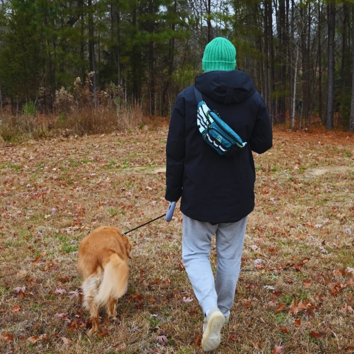 Walking a golden retriever with the Hip Pack worn crossbody and a teal beanie
